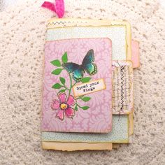 two greeting cards with butterflies on them sitting on a white surface next to a crochet doily