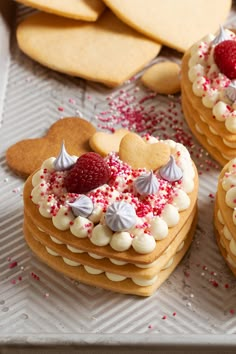 some heart shaped cookies with white frosting and red sprinkles on top