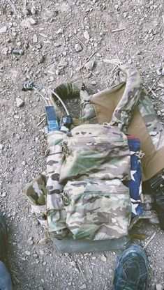 a backpack sitting on the ground next to someone's feet and shoes in the dirt