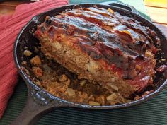 a cake in a skillet on top of a red towel next to a wooden spoon