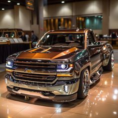 two pickup trucks are on display in a showroom with people looking at the cars