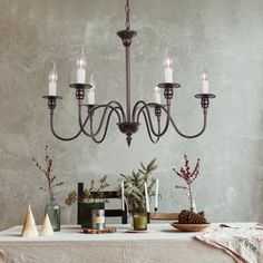 a chandelier hanging over a dining room table with christmas decorations on the table