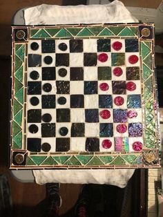 a piece of art that looks like a checkerboard board with red, green and black squares on it