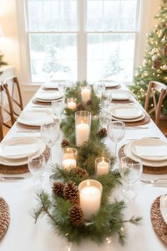 a table set for christmas with candles and pine cones