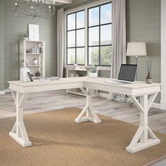 a computer desk with a laptop on top of it next to a book shelf and window