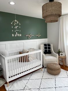 a baby's room with green walls and white furniture