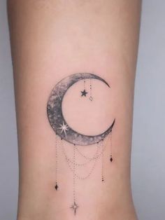 a small moon and stars tattoo on the side of a woman's leg,