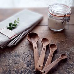 three wooden spoons sitting on top of a table next to a jar and napkin