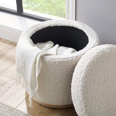 two white bean bags sitting on top of a wooden floor next to an open window