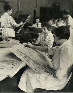 an old black and white photo of women working at desks in a sewing school