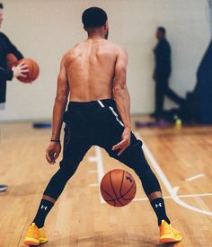 a man standing on top of a basketball court with a ball in his hand and two other men behind him