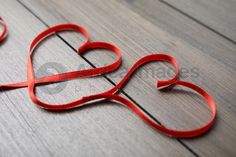 red ribbon shaped like two hearts on wooden floor