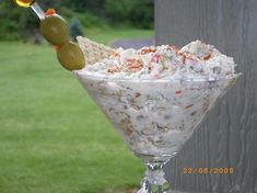 a glass filled with food sitting on top of a grass covered field