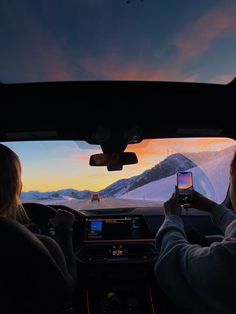 two people sitting in the back seat of a car looking at a cell phone screen