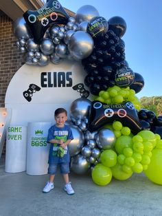 a young boy standing in front of a bunch of balloons