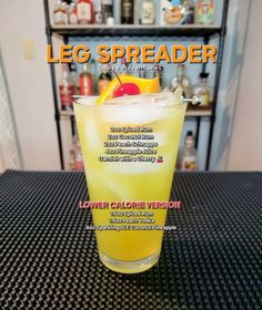 a tall glass filled with yellow liquid on top of a table