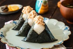 three pieces of sushi on a white plate with blue and gold trimmings