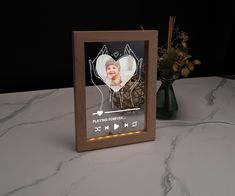 a wooden frame with a photo on it sitting on a table next to a vase filled with flowers