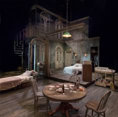 an old fashioned bedroom with a table and chairs in front of the bed, set up for a play