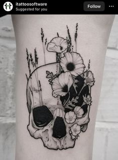 a black and white photo of a skull with flowers on it's side thigh