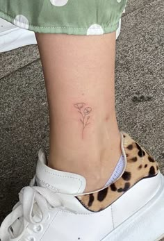 a woman's foot with a small flower tattoo on her left side calfal