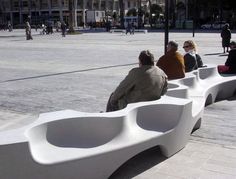 people sitting on benches in the middle of a plaza