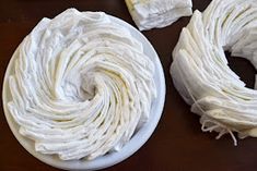 two white bowls filled with whipped cream on top of a wooden table