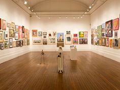 an art gallery filled with lots of paintings and pictures on the walls, along with wooden flooring