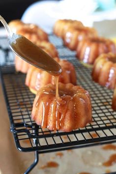 a spoon drizzling caramel sauce onto donuts on a cooling rack