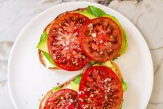 two slices of tomato and lettuce on a white plate