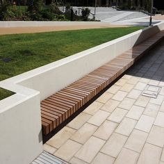 a wooden bench sitting on the side of a cement wall next to a grass covered field