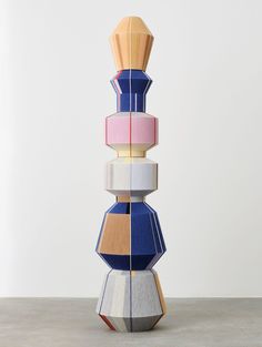 a stack of different colored objects on top of each other in front of a white wall