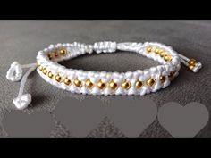 two white and gold beaded bracelets sitting on top of a gray tablecloth