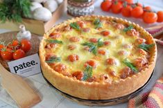 a pizza sitting on top of a table next to tomatoes and other food items in the background