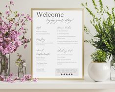 a welcome sign sitting on top of a table next to vases with flowers in them