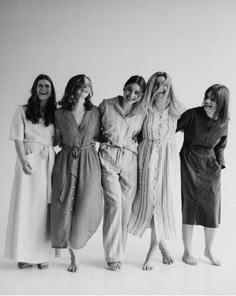 four women in long dresses are standing together