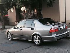 a silver car parked in front of a building next to a sidewalk with trees on it