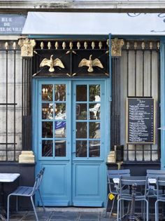 an outdoor cafe with blue doors and tables