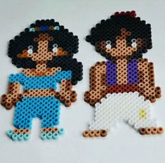 two pieces of perler bead art on a white surface with one being a boy and the other is a girl