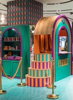 an exhibit with colorfully painted booths and gold poles in the center is a display case for books