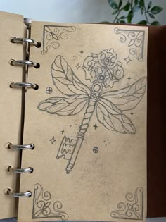 an open notebook with a drawing of a dragon holding a key on it's cover