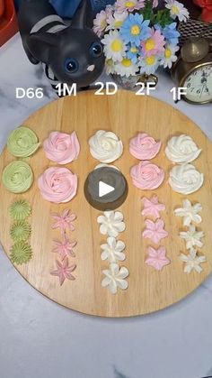 a wooden board topped with cupcakes on top of a table next to flowers