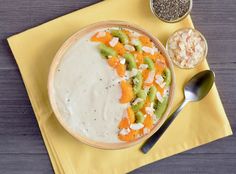 a bowl of cereal with kiwis and other toppings on a yellow napkin