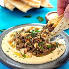 a person dipping some pita bread into a bowl