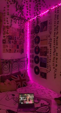 a laptop computer sitting on top of a bed in a room filled with posters and lights