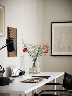 a vase with flowers sitting on top of a white desk