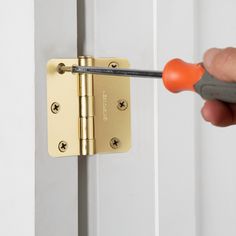 a person is holding a screwdriver and fixing a door handle on a white door