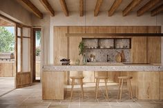 a large kitchen with wooden cabinets and marble counter tops, along with bar stools