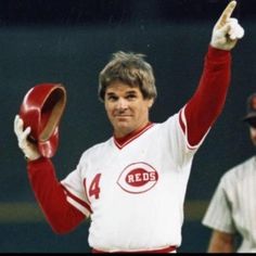 a baseball player is holding his hat up in the air