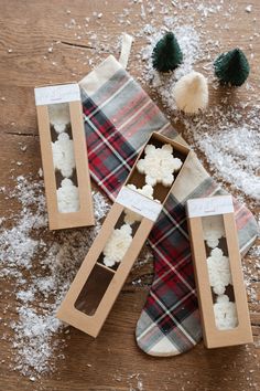 three small boxes filled with white snow on top of a wooden table next to christmas decorations